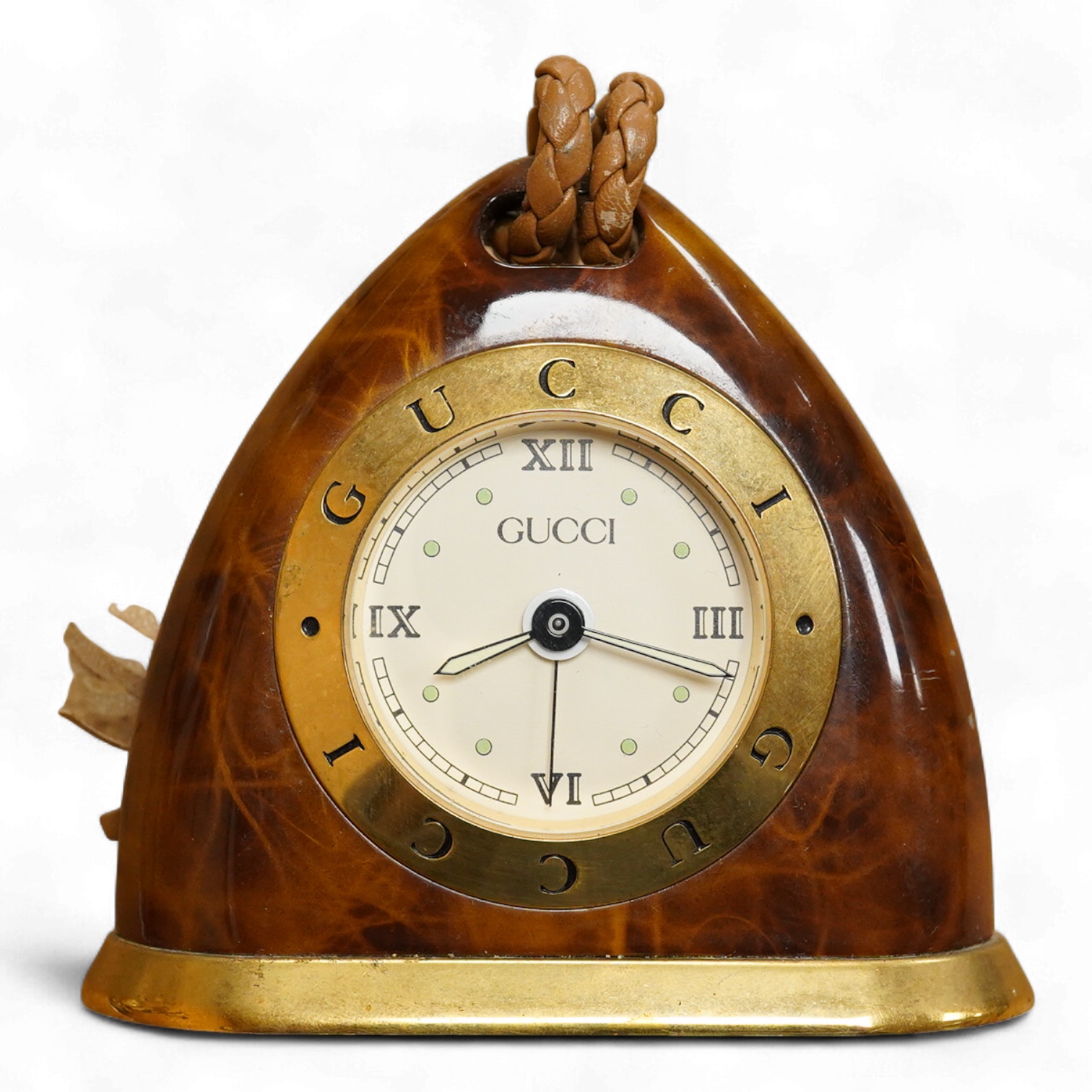 A Gucci gilt and enamelled stirrup shaped alarm clock with plaited and tasselled leather decoration, 9cm high